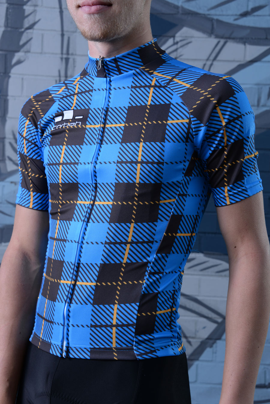 Rider wearing the Corbah Scotsman plaid jersey in front of a painted mural