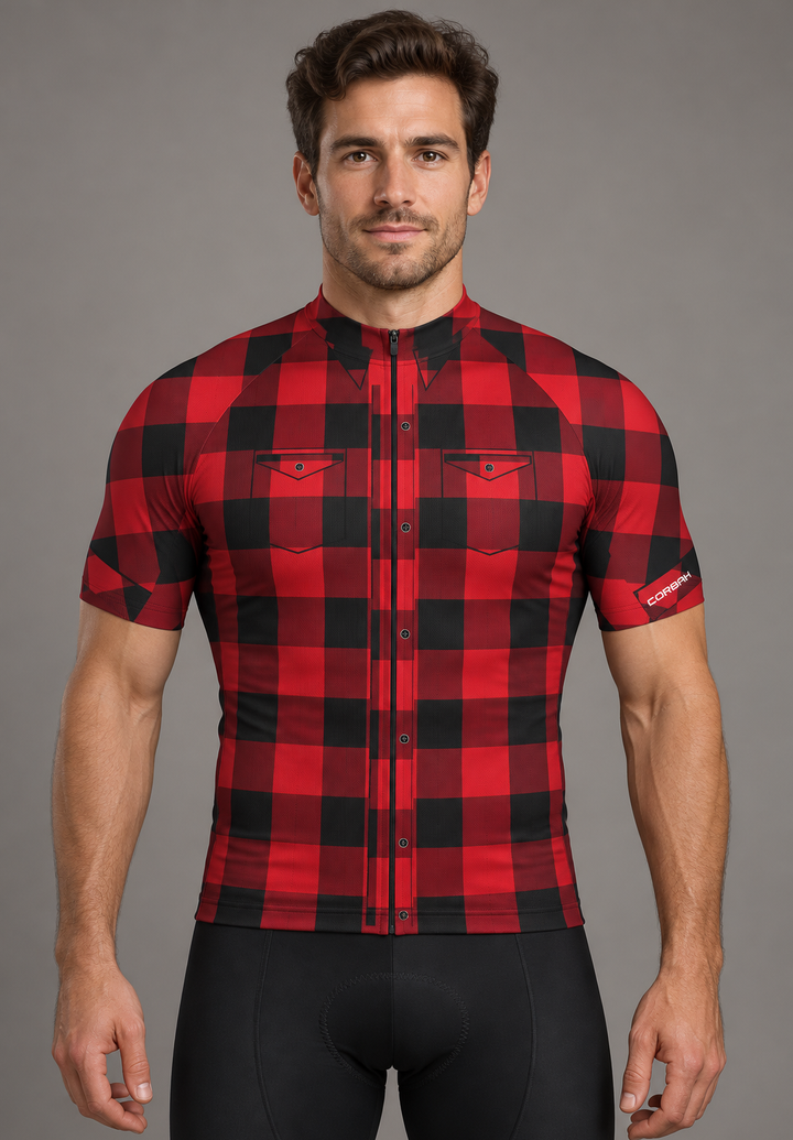 Rider wearing The Lumberjack cycling jersey: red and black buffalo check with printed button placket, chest pockets and collar points. Bib shorts sold separately.