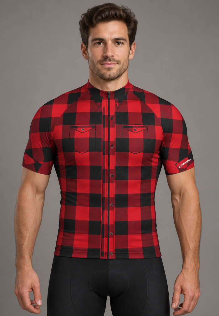 Rider wearing The Lumberjack cycling jersey: red and black buffalo check with printed button placket, chest pockets and collar points. Bib shorts sold separately.