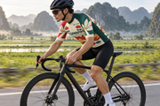 Side tracking visualization of a rider in the Việt Nam jersey passing green rice fields.