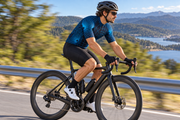 Side-profile cyclist in motion wearing the Wormhole jersey. AI visualization.