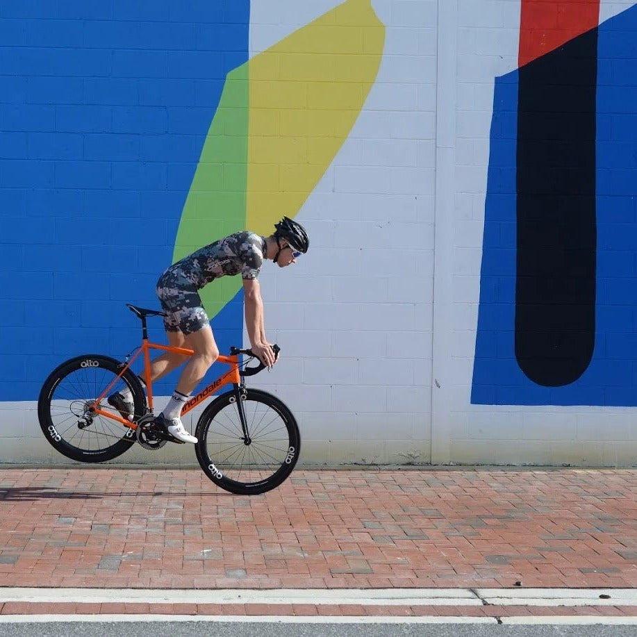 Rider in the Weekend Warrior XC racesuit riding past a bold painted wall.